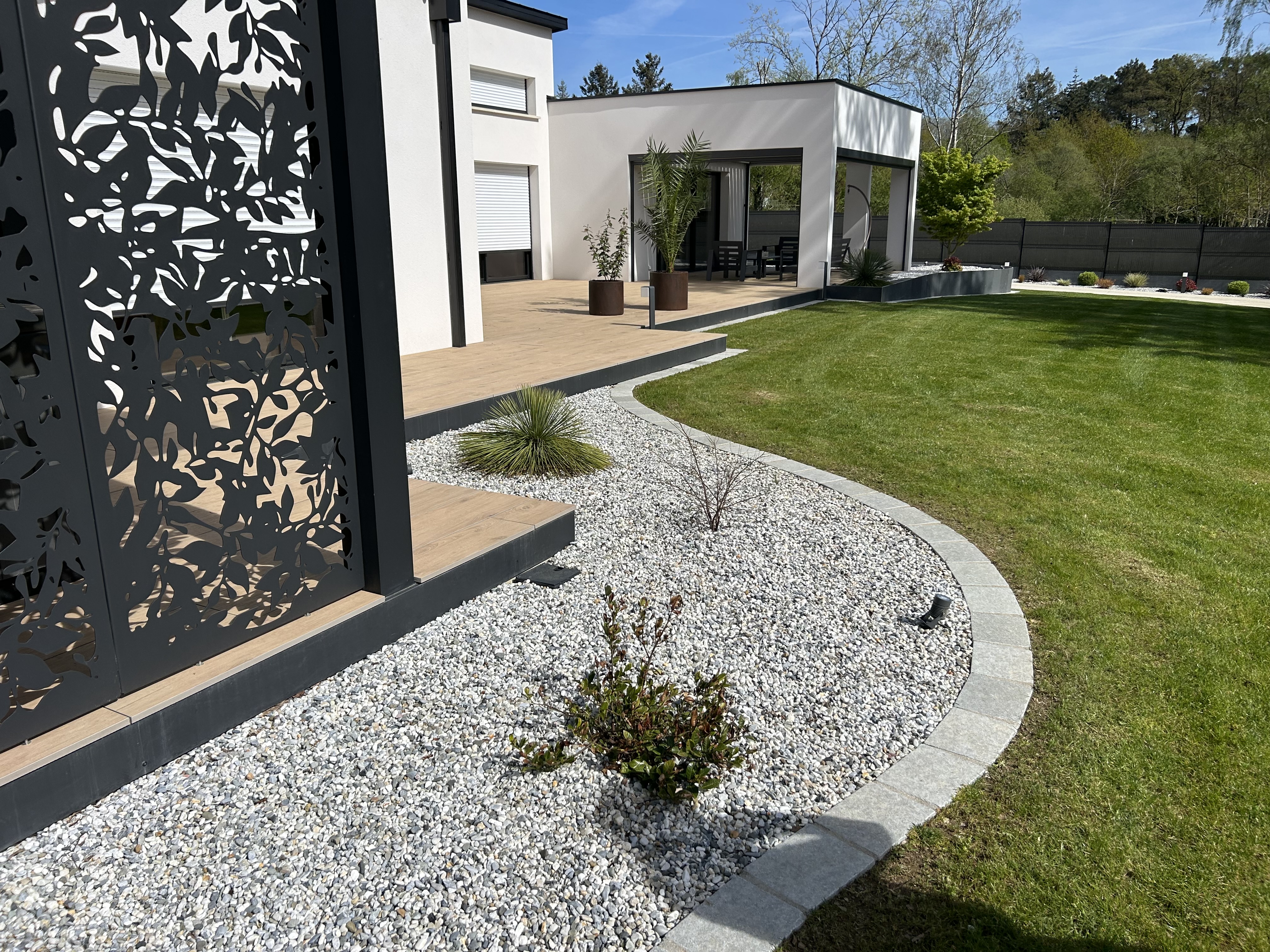 Jardin contemporain avec claustra découpé laser et terrasse bois